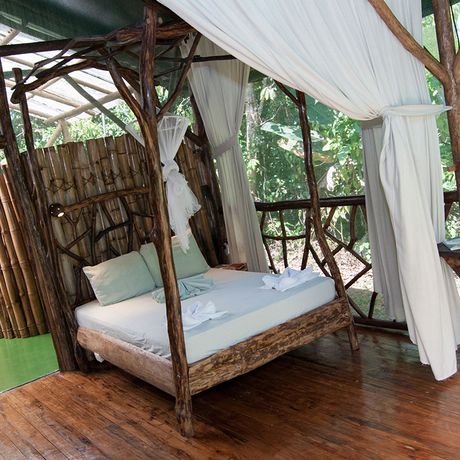 Blick auf das hölzerne Doppelbett im Bungalow der Duschungel-Lodge Danta Corcovado