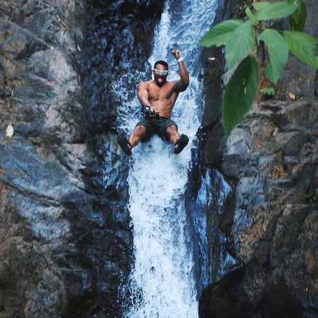 Blick auf einen Mann auf einem Wasserfall beim Tagesausflug Abwechslungsreiche Wasserfall-Tour