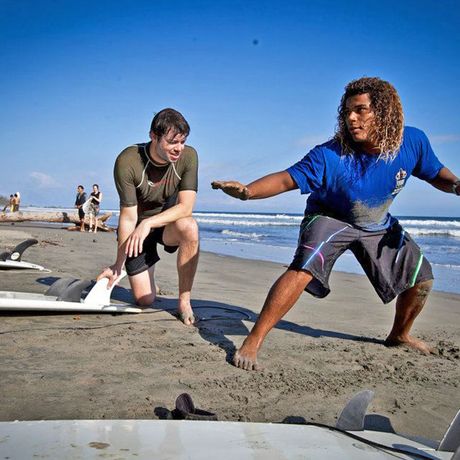 Blick auf Mann bei Trockenübungen mit Surflehrer am Strand